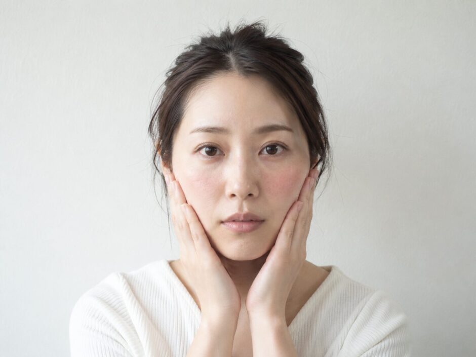 赤みのある頬に両手を添えている女性